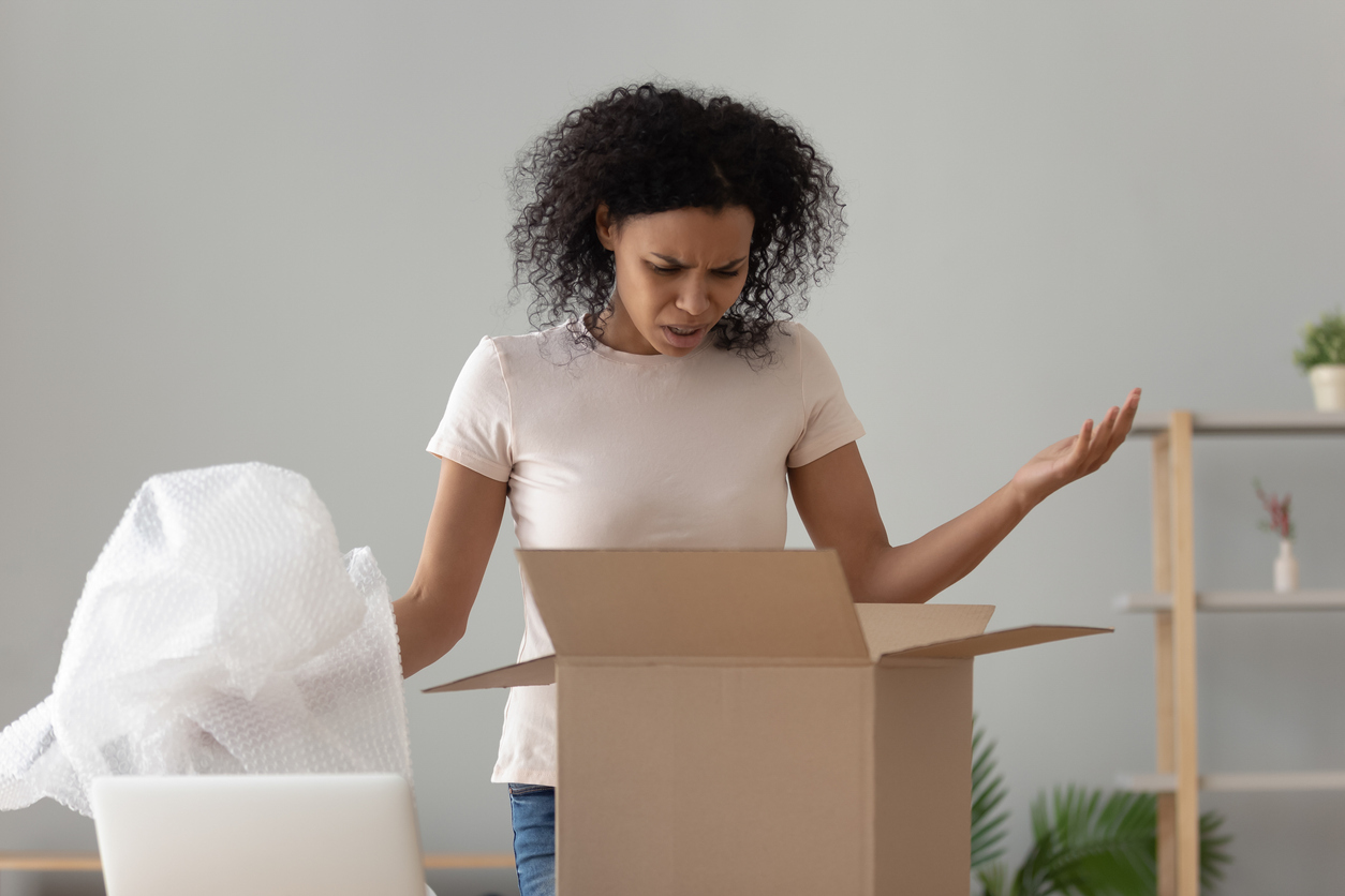 overpackaging — Disappointed shocked african woman open cardboard box receive bad parcel