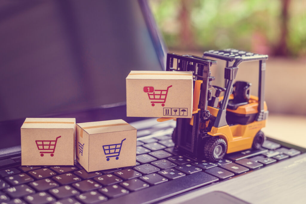contract packaging services — Logistics and supply chain management for online shopping concept : Fork-lift moves a box with a red shopping cart logo, 2 cartons on a laptop computer.